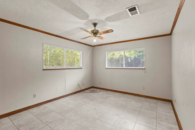 an empty room with chandelier fan and windows