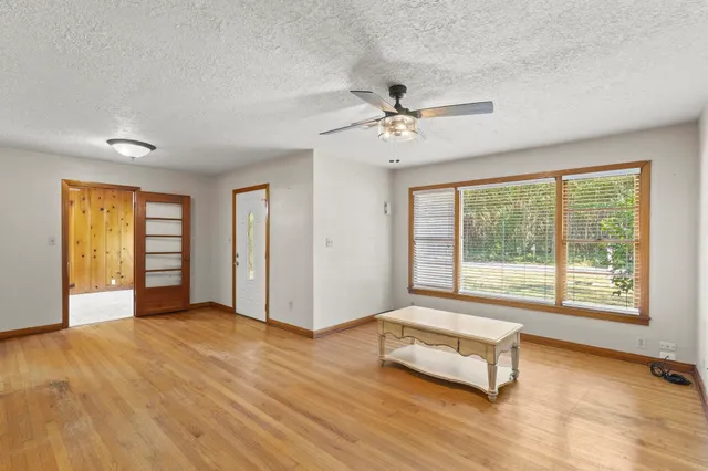 a view of an empty room with a window and wooden floor