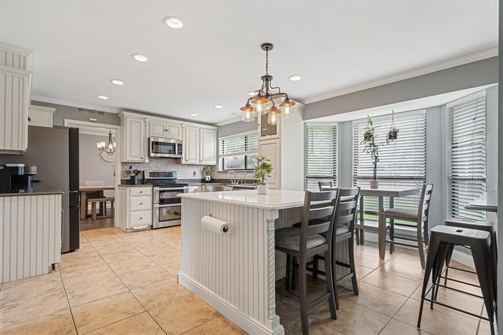 303 Hopewell Street Grand Prairie, TX 75052 - Photo 7 of 28 a kitchen with stainless steel appliances kitchen island granite countertop a stove refrigerator a sink dishwasher a dining table and chairs with wooden floor