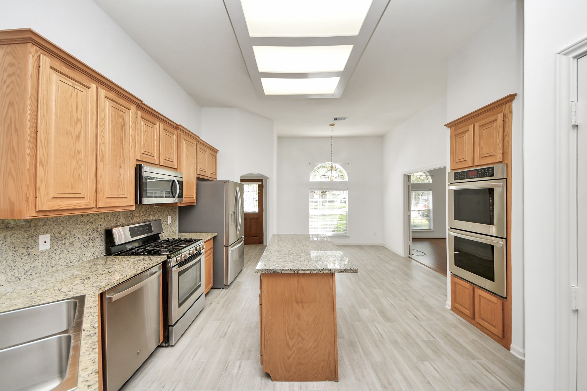 5815 Pheasant Ridge Lane Houston, TX 77041 - Photo 24 of 46 Spacious kitchen with granite countertops, modern stainless steel appliances, and abundant natural light, featuring a central island and warm wood cabinetry.