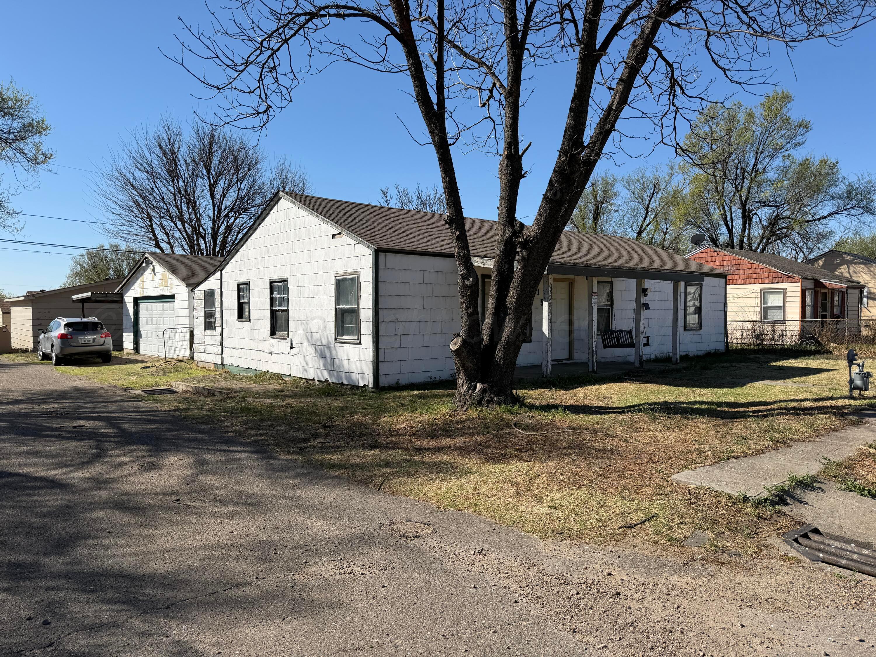 215 Hickory Street Borger, TX 79007 - Photo 2 of 18 a view of a white house with a large tree next to a yard