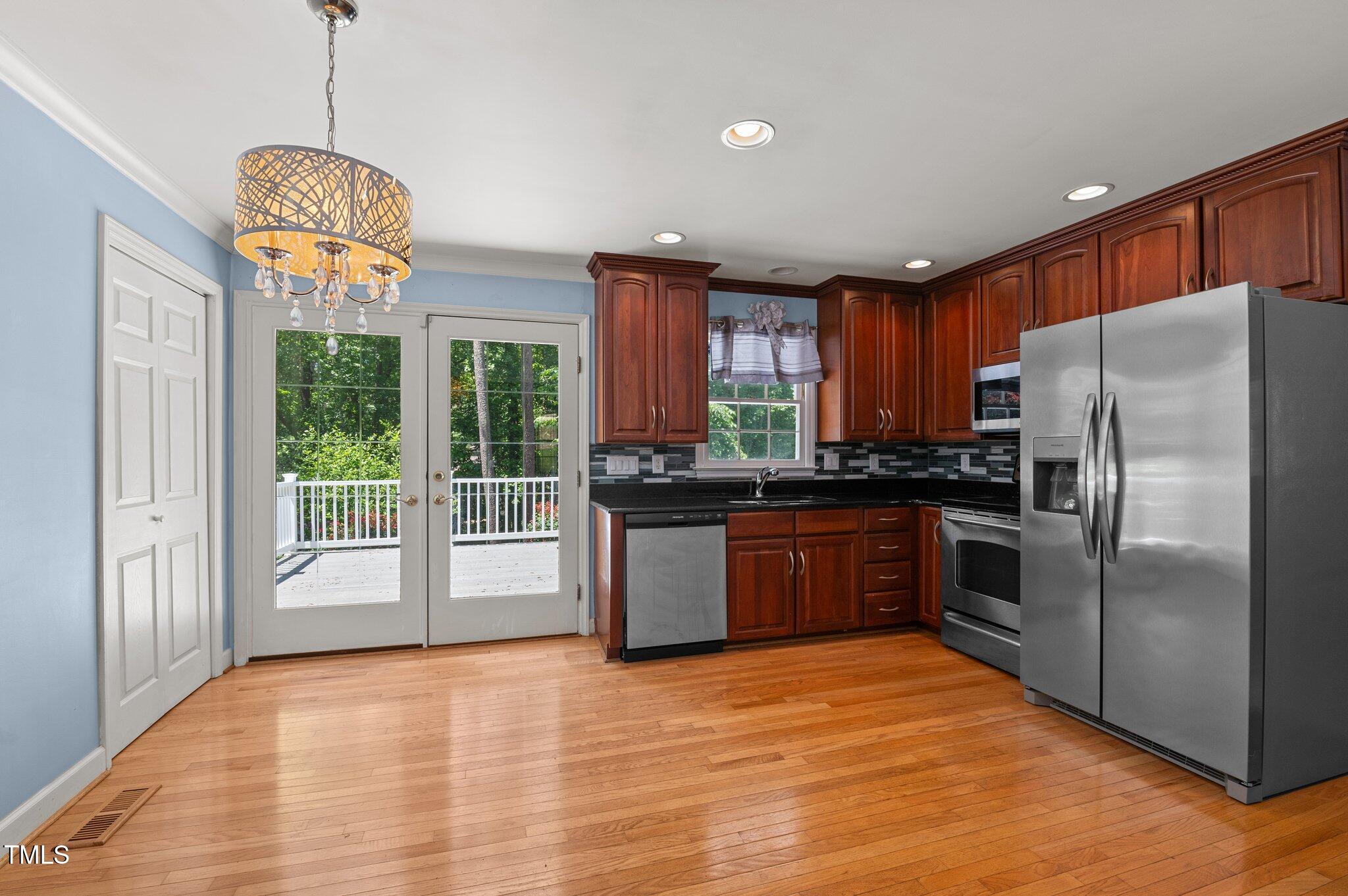 612 Harvest Lane Raleigh, NC 27606 - Photo 9 of 38 a kitchen with stainless steel appliances granite countertop a refrigerator a sink dishwasher a stove and a large window with wooden floor