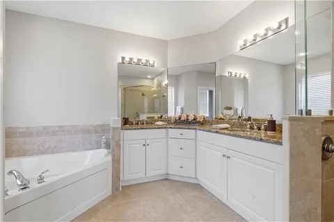 a bathroom with a bathtub a double vanity sink and a mirror