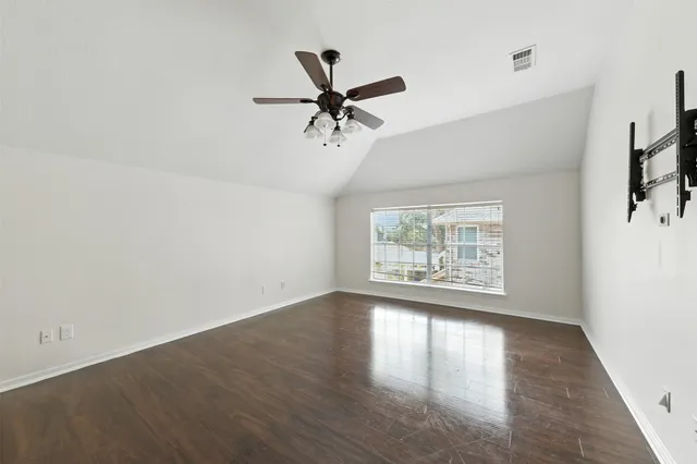 an empty room with wooden floor fan and windows
