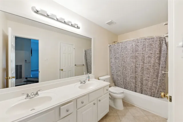 a bathroom with a double vanity sink toilet mirror and shower