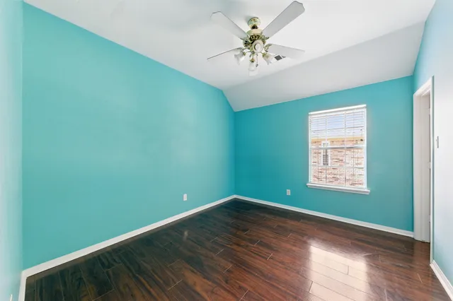 a view of an empty room with window and wooden floor