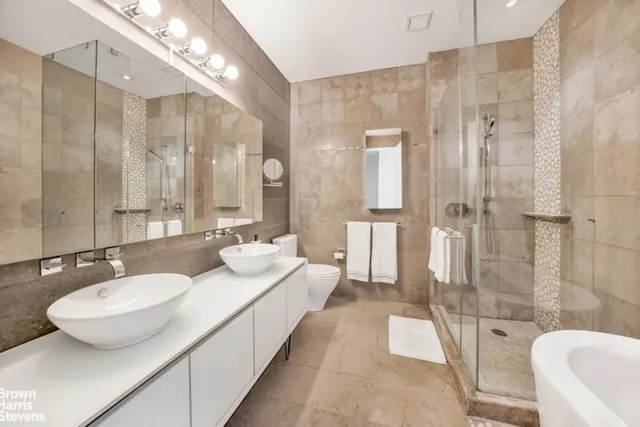 a spacious bathroom with a granite countertop sink a toilet a mirror and shower