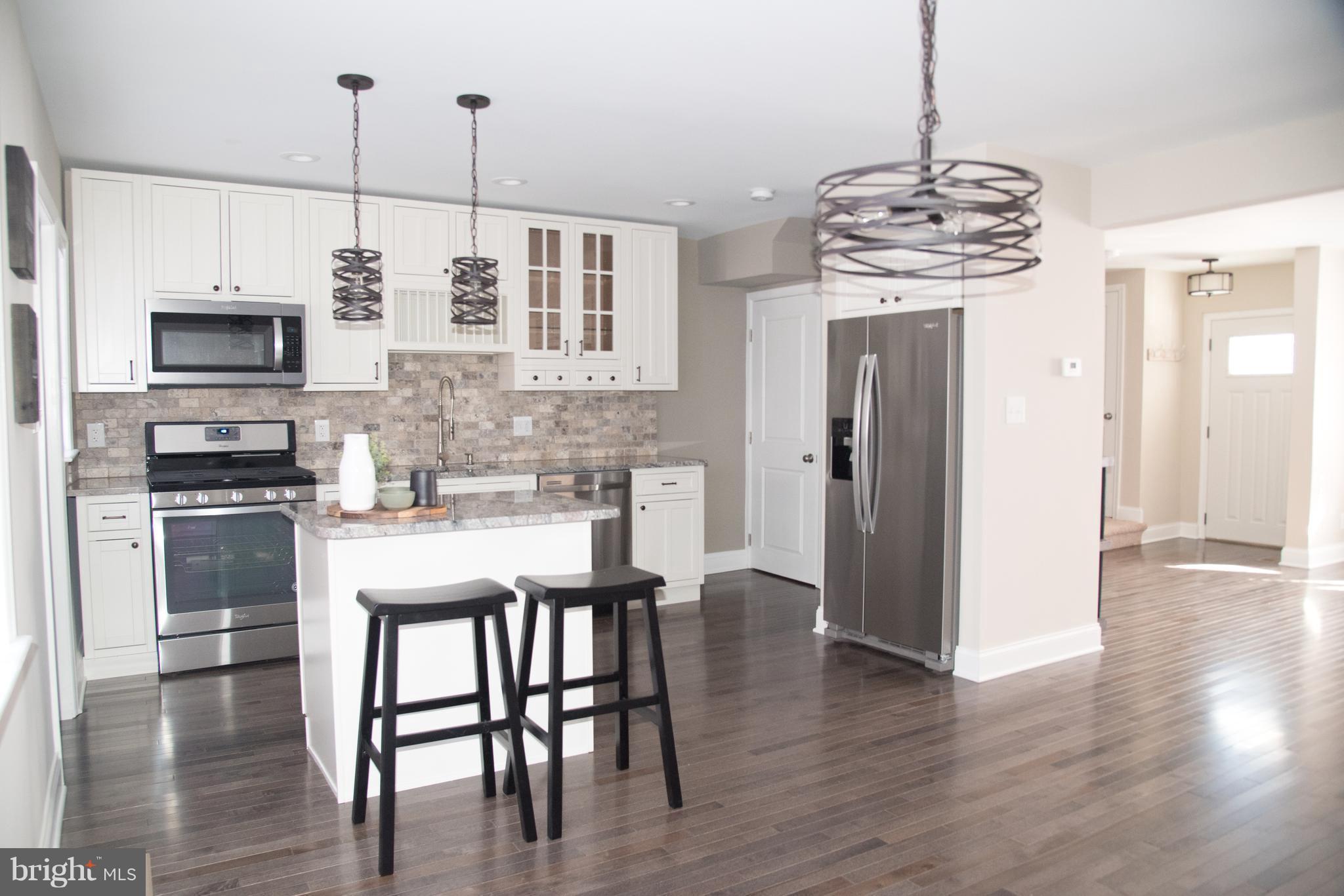 4130 Fairfax Road Baltimore, MD 21216 - Photo 7 of 30 a kitchen with stainless steel appliances a kitchen island hardwood floor and chairs