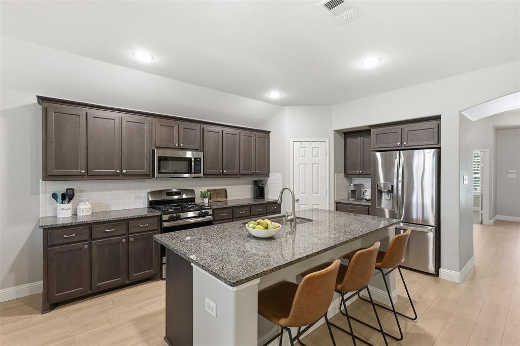 717 Allbright Road Celina, TX 75009 - Photo 5 of 37 Large island, walk in pantry, open to the living room and breakfast area, gas stove top, oven and granite counter tops