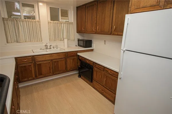 a kitchen with stainless steel appliances granite countertop a refrigerator a sink dishwasher a stove top oven a refrigerator and cabinets