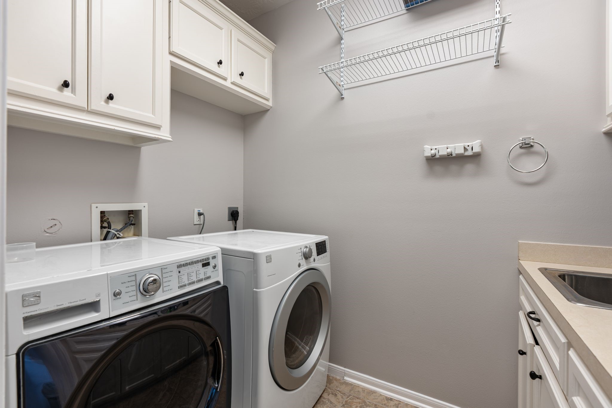 3822 Merrick Street Houston, TX 77025 - Photo 22 of 34
The laundry room is conveniently located upstairs and features white upper cabinetry for storage, a utility sink with countertop, wire shelving on the adjacent wall, tile flooring, and dedicated connections for a full-size front-load washer and dryer.