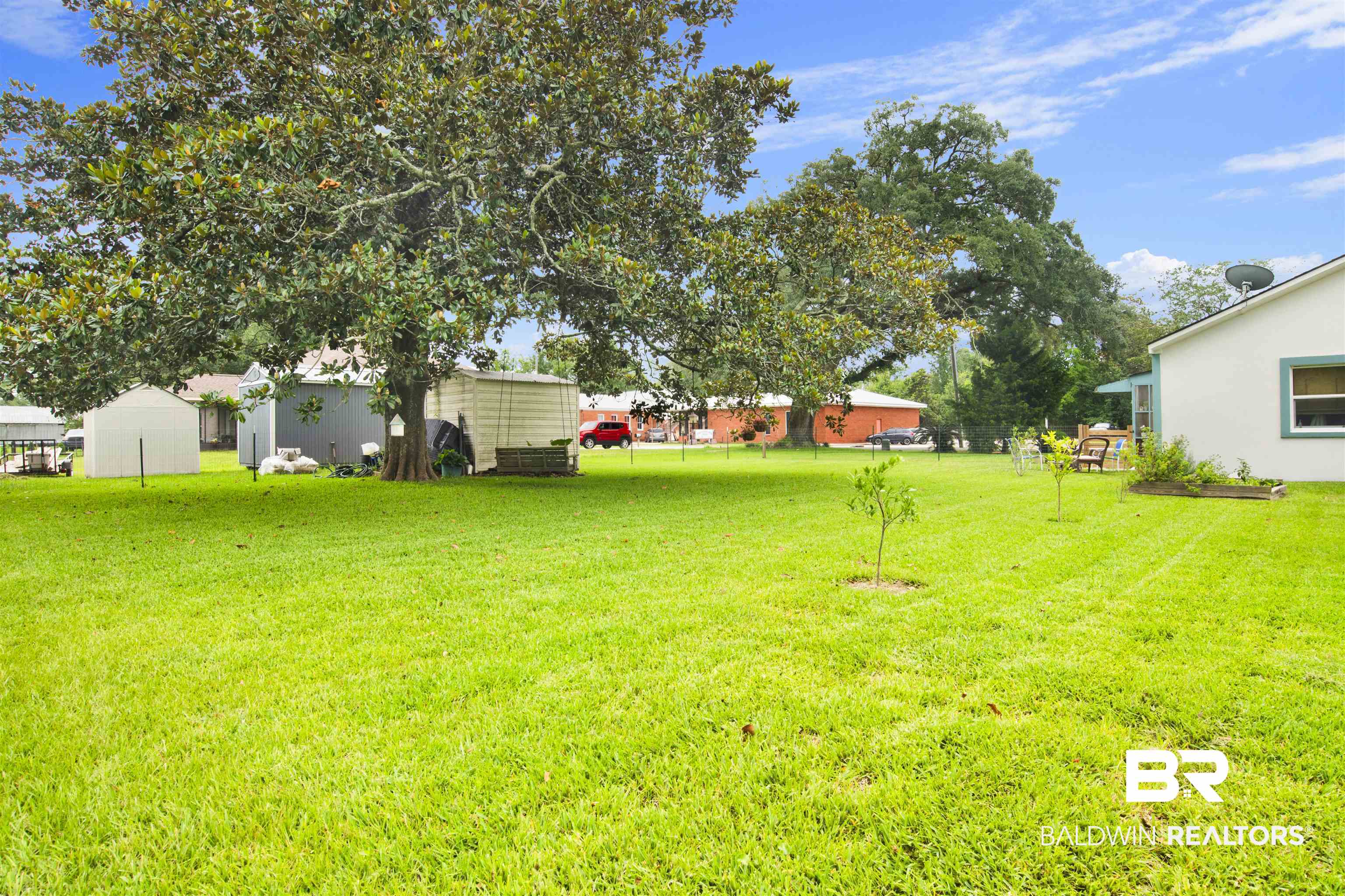 1100 North Pine Street Foley, AL 36535 - Photo 30 of 30 Expansive backyard featuring a large established tree, a manicured lawn, and two permanent storage sheds