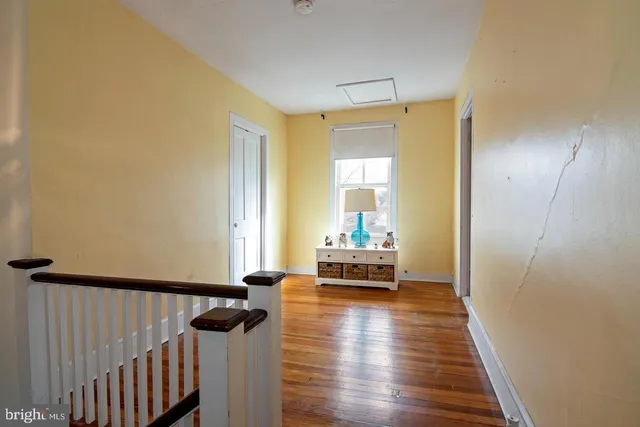 a view of a hallway with wooden floor and furniture