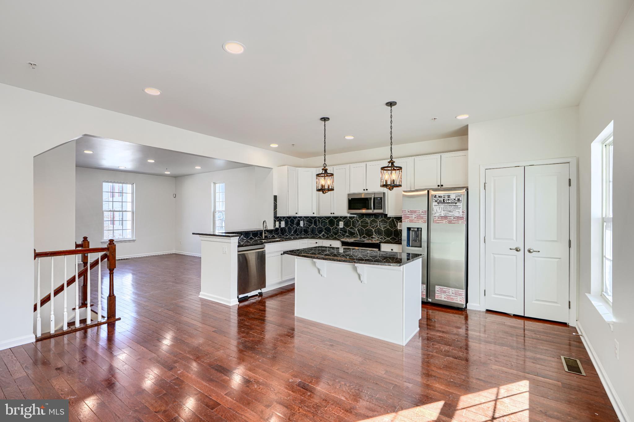 7366 Matchbox Alley Elkridge, MD 21075 - Photo 12 of 32 a kitchen with stainless steel appliances kitchen island hardwood floor sink and stove