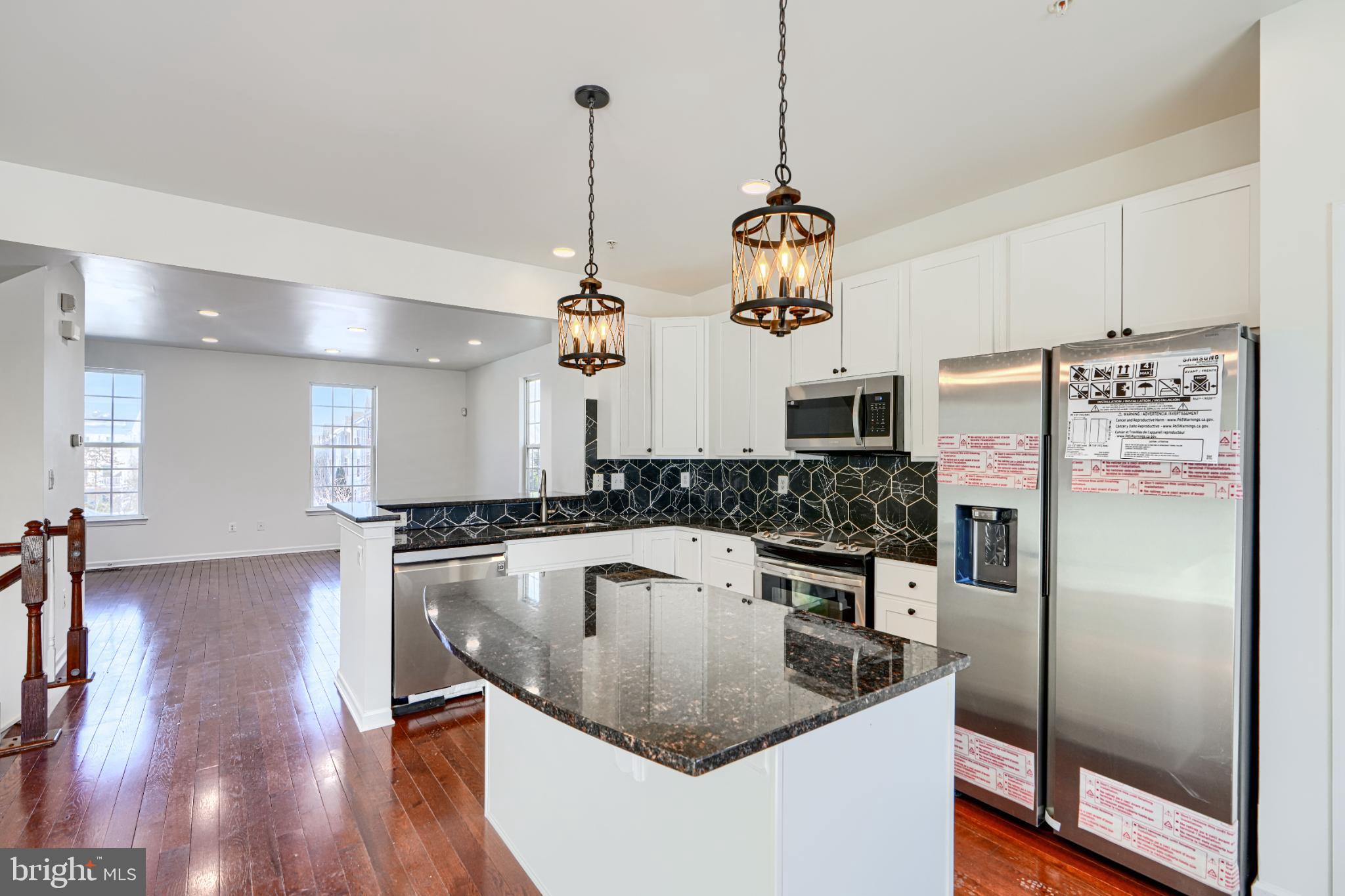 7366 Matchbox Alley Elkridge, MD 21075 - Photo 13 of 32 a kitchen with stainless steel appliances granite countertop a sink a refrigerator and a wooden floor