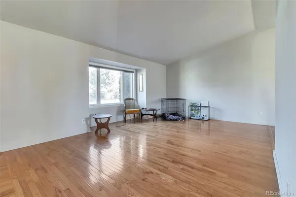 a living room with furniture and a dining table with wooden floor