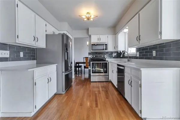 a kitchen with cabinets a wooden floor and stainless steel appliances