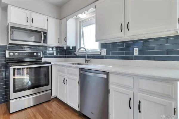 a kitchen with cabinets stainless steel appliances a sink and wooden floor