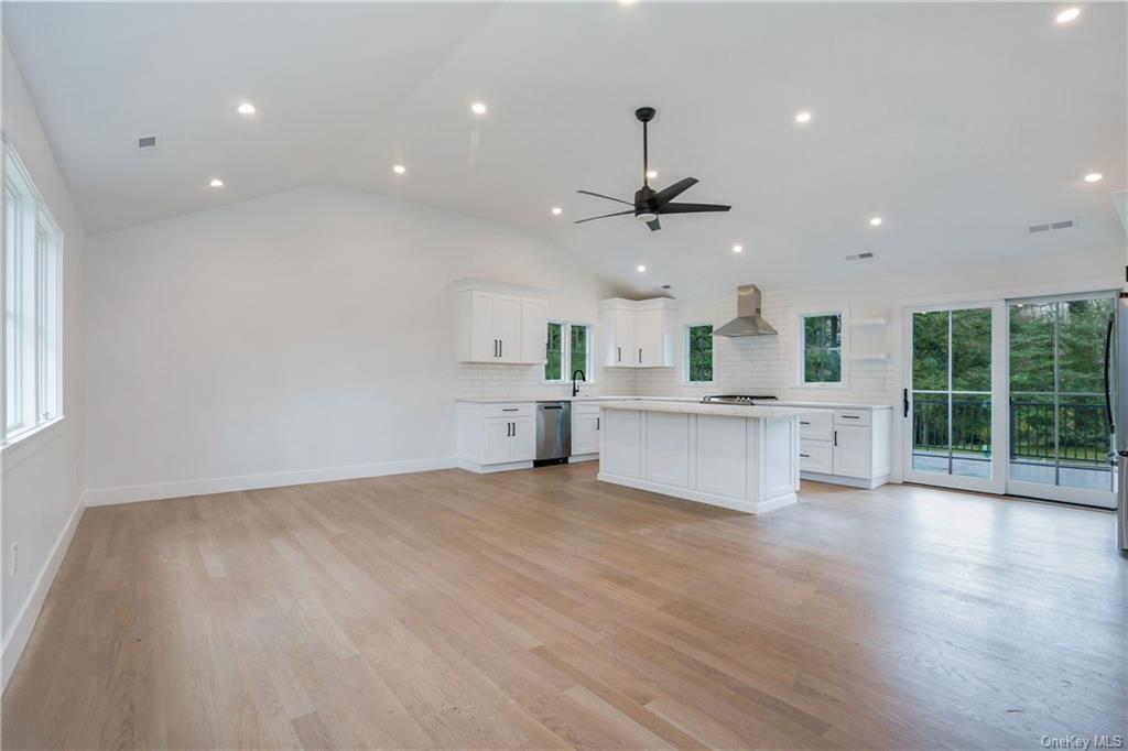 a large kitchen with stainless steel appliances a large counter top a large window and wooden floor