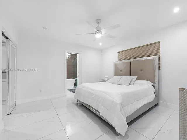 a large bedroom with a large bed and a chandelier fan