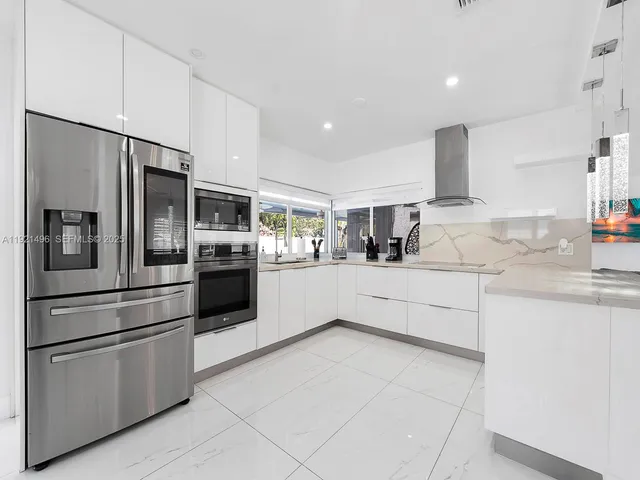 a kitchen with stainless steel appliances kitchen island granite countertop a refrigerator and a sink
