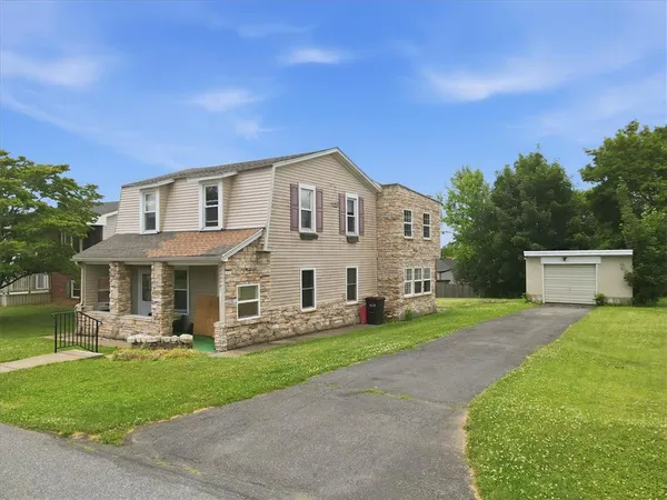 a front view of a house with a yard and trees