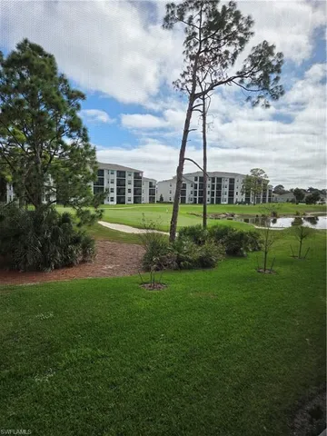 a view of a big yard with a fountain and large trees