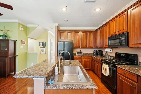 a kitchen with stainless steel appliances granite countertop a stove top oven a sink dishwasher a dining table and chairs with wooden floor