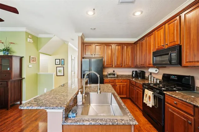 a kitchen with stainless steel appliances granite countertop a stove top oven a sink dishwasher a dining table and chairs with wooden floor