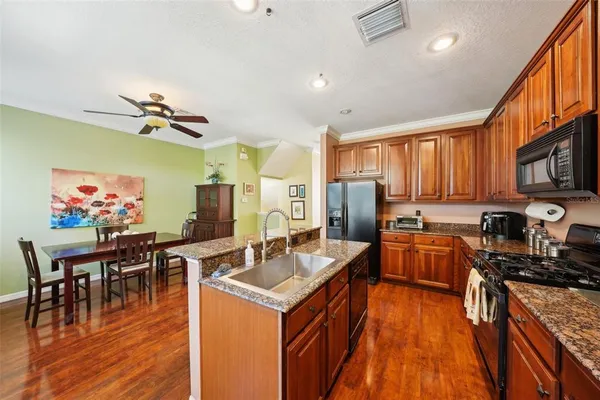 a open kitchen with stainless steel appliances granite countertop a sink dishwasher and a dining table with wooden floor