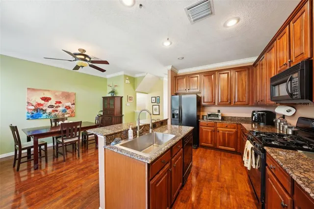 a open kitchen with stainless steel appliances granite countertop a sink dishwasher and a dining table with wooden floor