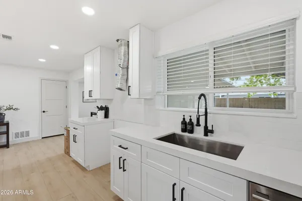 a kitchen with white cabinets a sink a window and stainless steel appliances