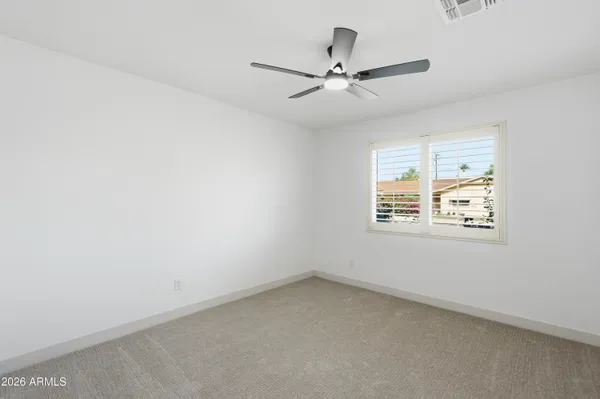 an empty room with a window and a fan