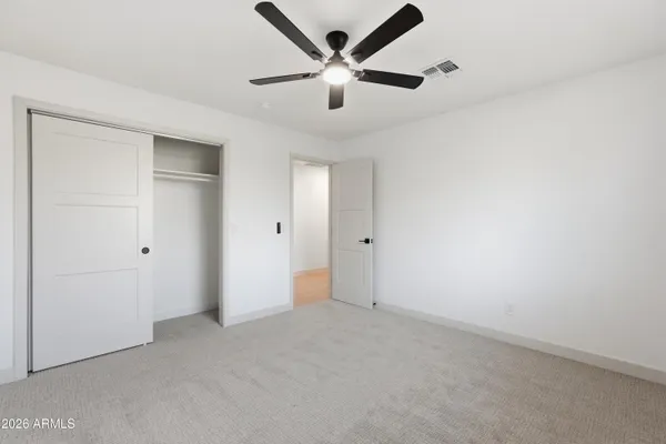 an empty room with closet and a ceiling fan