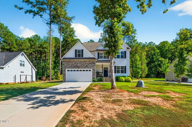 a view of a house with a big yard and large trees