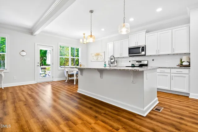 a kitchen with stainless steel appliances kitchen island granite countertop a sink a stove and cabinets