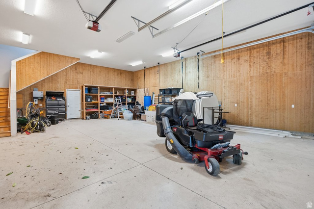 672 Perry Hollow Drive Mapleton, UT 84664 - Photo 84 of 106 Spacious garage featuring concrete flooring, wood paneling, an interior staircase, overhead lighting, and built-in shelving