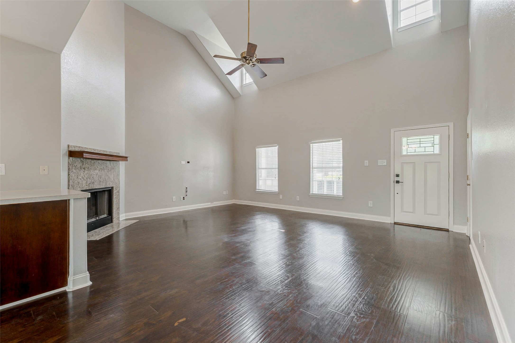 8411 Syms Street Fulshear, TX 77441 - Photo 10 of 29 an empty room with wooden floor fireplace and windows