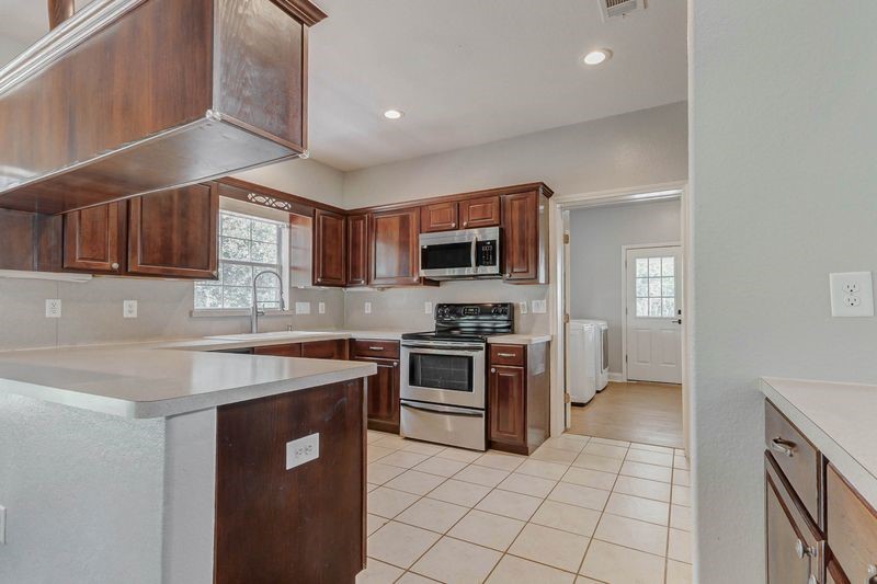 8411 Syms Street Fulshear, TX 77441 - Photo 14 of 29 a kitchen with a sink a stove top oven and cabinets