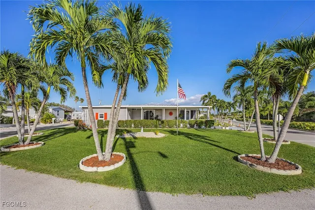 a front view of a house with garden and trees