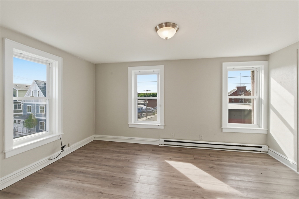 293 Clemente Street, Unit 3R Holyoke, MA 01040 - Photo 7 of 14 an empty room with wooden floor and windows