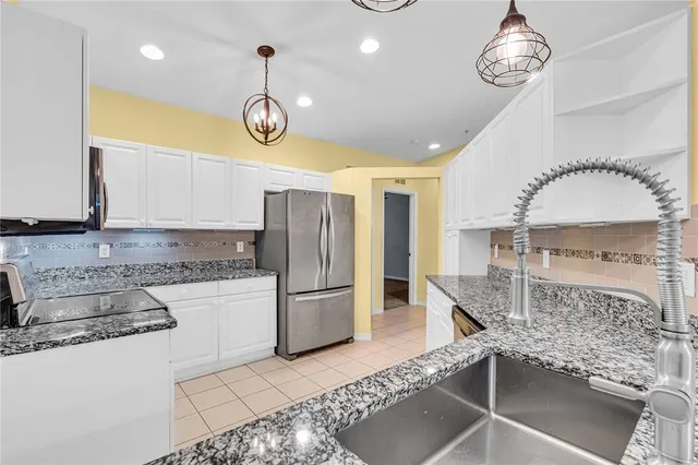 a kitchen with granite countertop white cabinets and stainless steel appliances