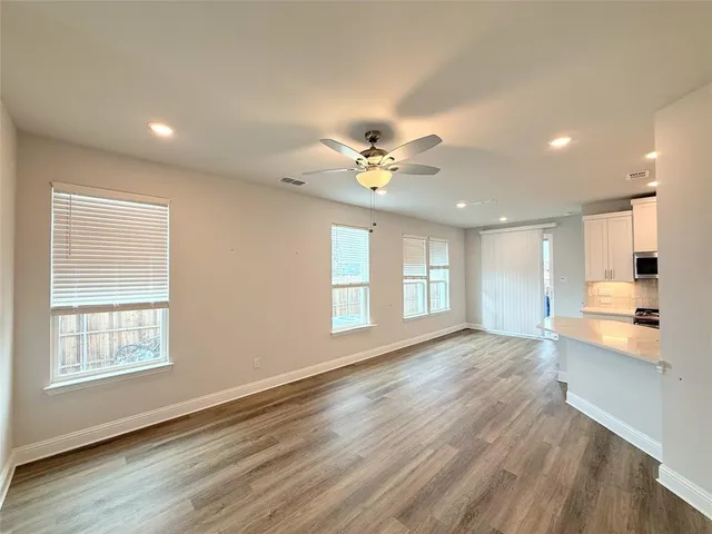a view of an empty room with a window and wooden floor