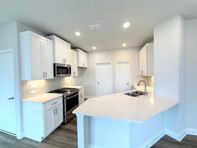 a kitchen with stainless steel appliances kitchen island granite countertop a sink stove and refrigerator