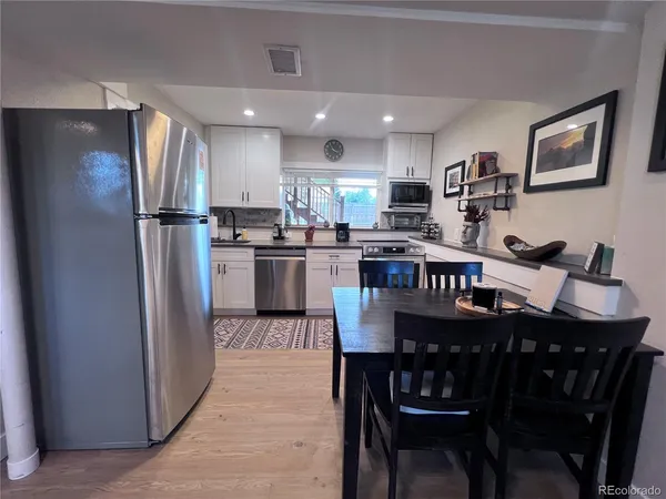 a kitchen with stainless steel appliances granite countertop a dining table chairs refrigerator and microwave