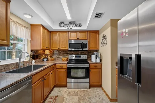 a kitchen with stainless steel appliances granite countertop a refrigerator a sink and a stove