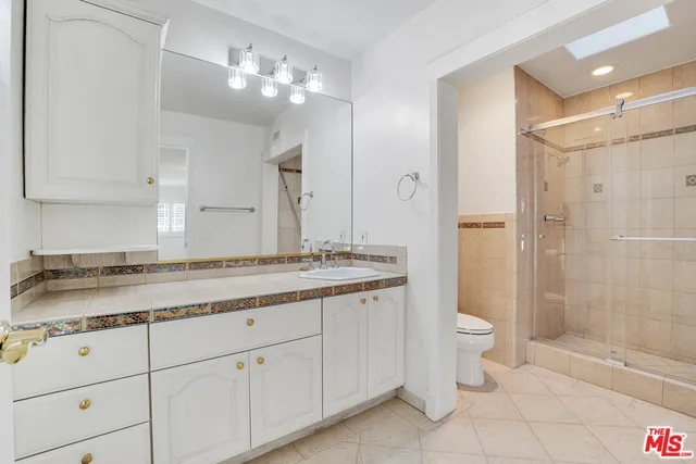a bathroom with a granite countertop sink a toilet and shower