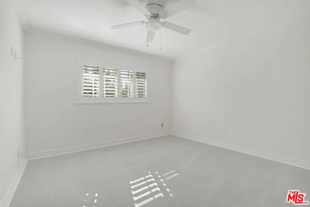 an empty room with a window and a fan