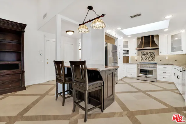 a view of kitchen with stainless steel appliances kitchen island dining table and chairs