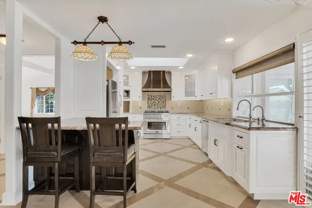 a kitchen with stainless steel appliances granite countertop a stove top oven a sink a dining table and chairs